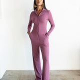 Woman wearing a purple jumpsuit standing against a white background