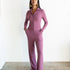 Woman wearing a purple jumpsuit standing against a white background